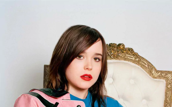 HD PC desktop wallpaper: celebrity portrait (identity unspecified) of a young woman with short dark hair and red lipstick, wearing a pink-and-blue jacket, seated on an ornate white chair.