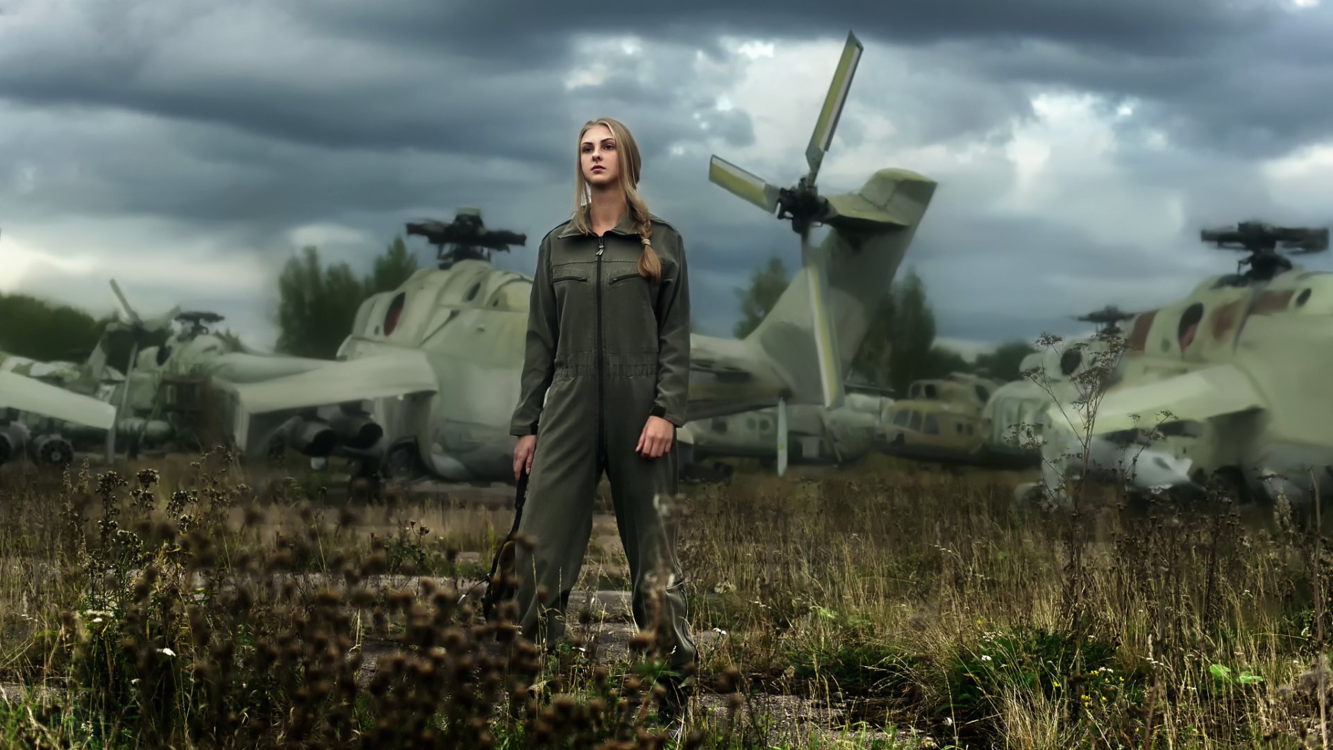 A blonde female soldier stands confidently in front of military helicopters against a dramatic sky, embodying strength and resilience in this HD desktop wallpaper.