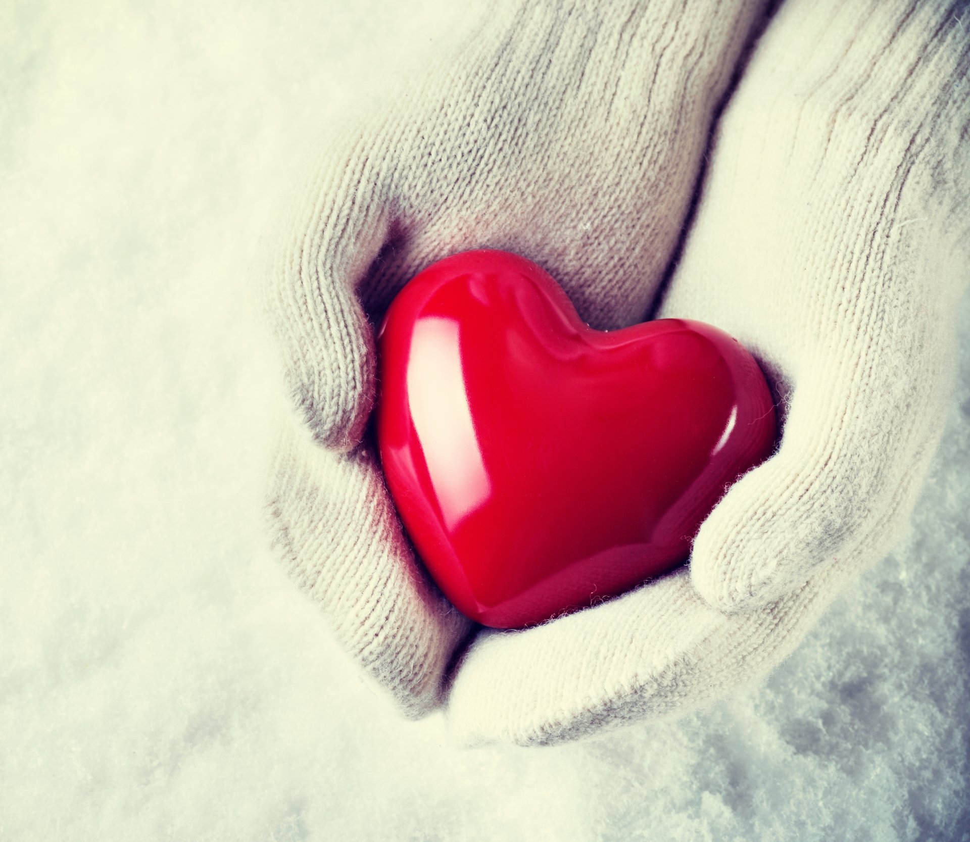 Artistic close-up of gloved hands gently holding a glossy red heart, captured in stunning 4K Ultra HD as a PC desktop wallpaper and background.