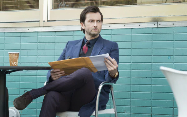 David Tennant as the Purple Man from the TV show Jessica Jones, seated outdoors with documents, featured in an HD PC desktop wallpaper and background.