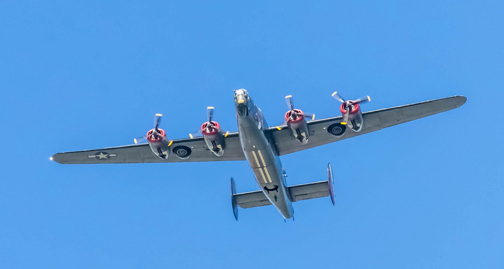 HD desktop wallpaper featuring a Consolidated B-24 Liberator military bomber aircraft flying against a clear blue sky.