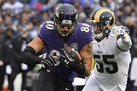 HD PC desktop wallpaper: Baltimore Ravens player carrying the ball as an opposing defender attempts a tackle in a high-energy NFL sports action shot.