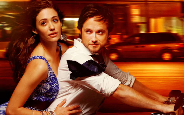 Fiona Gallagher and Jimmy Lishman from the TV show Shameless embrace in a vibrant, dynamic scene, set against a backdrop of city lights, creating a striking HD desktop wallpaper.