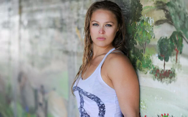 Ronda Rousey stands confidently against a vibrant mural, capturing the spirit of sports. This HD desktop wallpaper showcases her strong persona and athleticism.