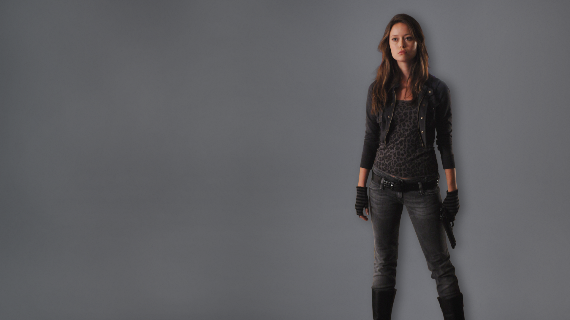 HD PC desktop wallpaper: a female character from the TV series Terminator: The Sarah Connor Chronicles stands in a black outfit against a plain gray background.