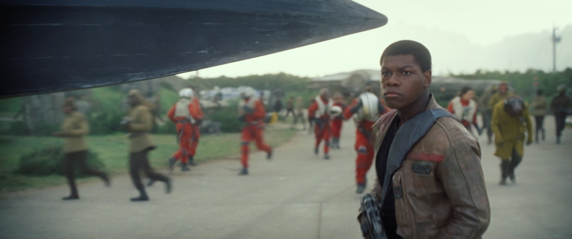 HD PC wallpaper featuring John Boyega as Finn from Star Wars Episode VII: The Force Awakens, set against a backdrop of pilots preparing for departure.
