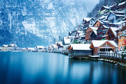 Snow-covered Hallstatt village nestled between a serene lake and towering Austrian mountains in winter, captured in HD for a stunning desktop background.