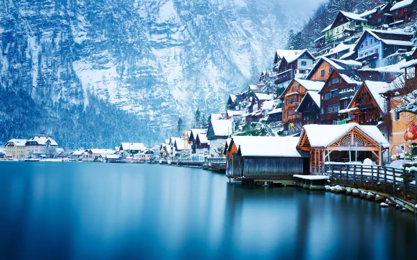 Snow-covered Hallstatt village nestled between a serene lake and towering Austrian mountains in winter, captured in HD for a stunning desktop background.