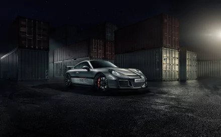 Silver Porsche 911 GT3 supercar parked on wet ground with stacked shipping containers in the background, captured in a high-definition desktop wallpaper style.