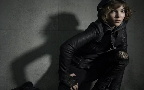 Camren Bicondova as Catwoman in the TV show Gotham, featuring a dynamic pose against a shadowy backdrop. An 8K Ultra HD wallpaper showcasing a striking and moody aesthetic.