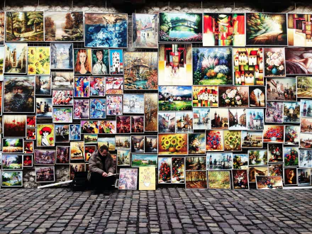 Colorful, artistic paintings displayed on a wall with a person sitting nearby, captured in a high-definition PC desktop wallpaper and background.