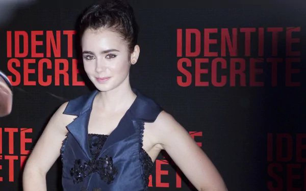 Portrait of an actress posing at a red-and-black Identité Secrète premiere backdrop; high-resolution 2K Quad HD PC desktop wallpaper/background.