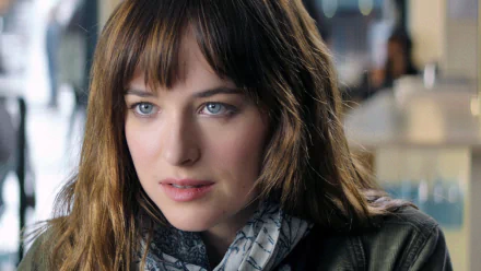 HD desktop wallpaper featuring Dakota Johnson from the movie Fifty Shades of Grey, showing a close-up of her with a thoughtful expression and soft lighting in the background.