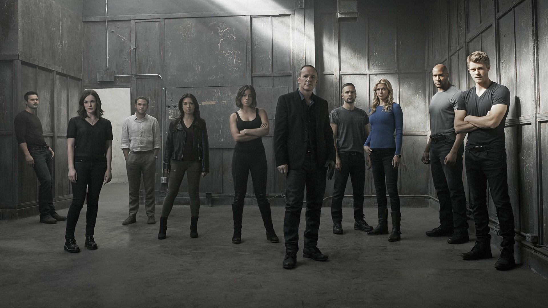 HD desktop wallpaper featuring the main cast of the TV show Agents of S.H.I.E.L.D. standing confidently in an industrial, dimly lit setting.