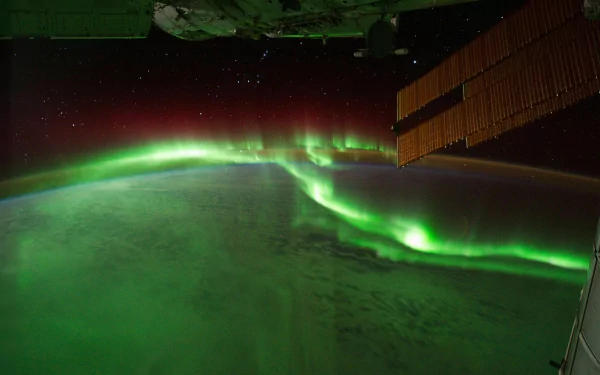 4K Ultra HD desktop wallpaper showcasing vibrant green aurora borealis glowing over Earth, captured from space with part of a satellite structure visible.