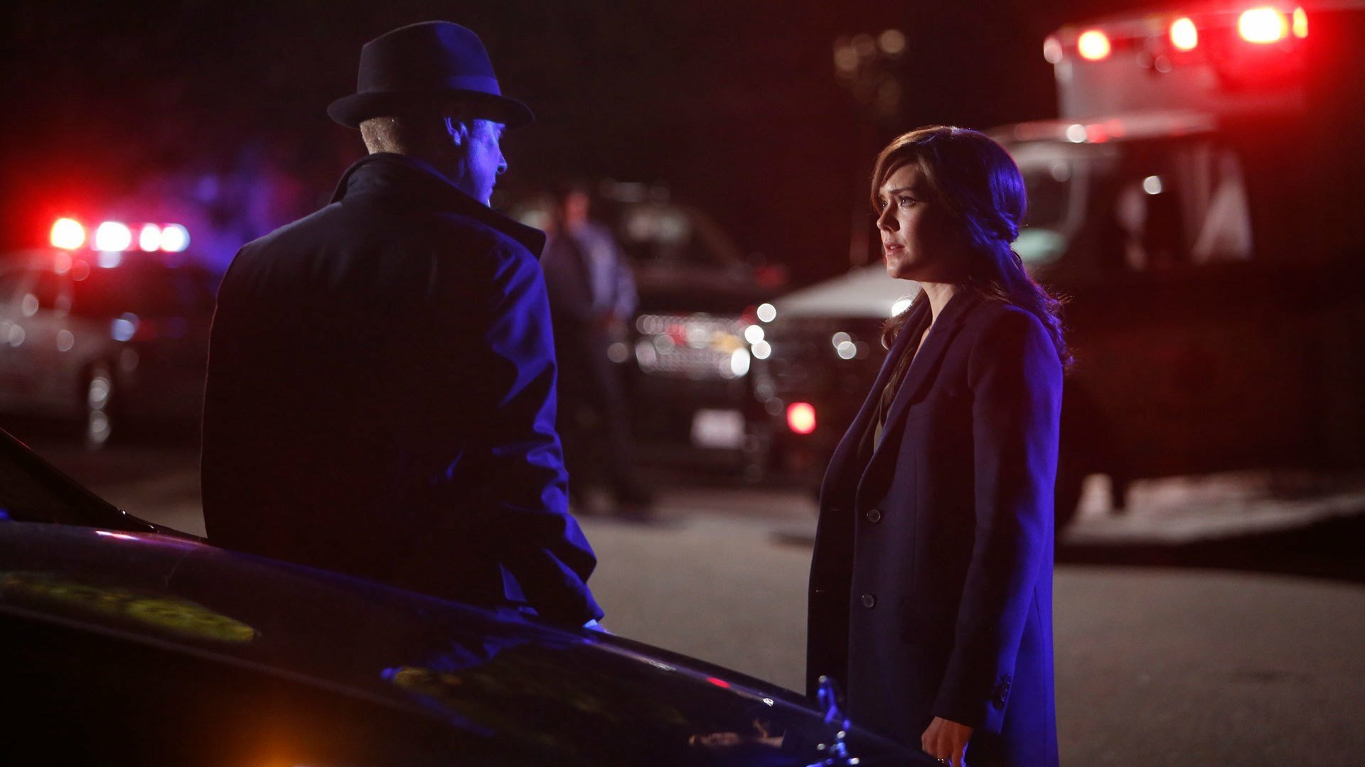 HD PC desktop wallpaper/background: moody scene from TV show The Blacklist — a fedora-clad man and a woman converse by police cars and an ambulance at night.