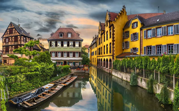 A vibrant HD desktop wallpaper of colorful historic buildings along a canal in Colmar, France, showcasing charming man-made architecture and serene water reflections.