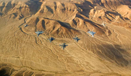 A formation of military jet fighters soars over a rugged desert landscape; HD desktop wallpaper background.