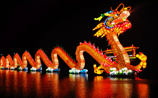 A vibrant Chinese dragon illuminated with colorful lights glides across the water, celebrating the festive spirit of the Chinese New Year. This stunning HD wallpaper captures the holiday's essence.