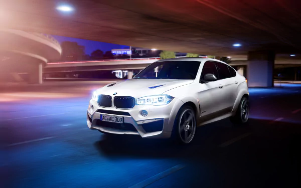 A white BMW X6 SUV driving at night under a curved overpass, captured in a dynamic HD desktop wallpaper showcasing the vehicle's sleek design.