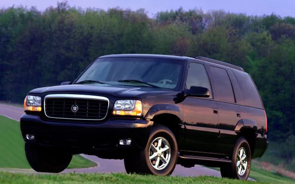 HD PC desktop wallpaper of a black Cadillac Escalade vehicle on a country road, front three-quarter view.