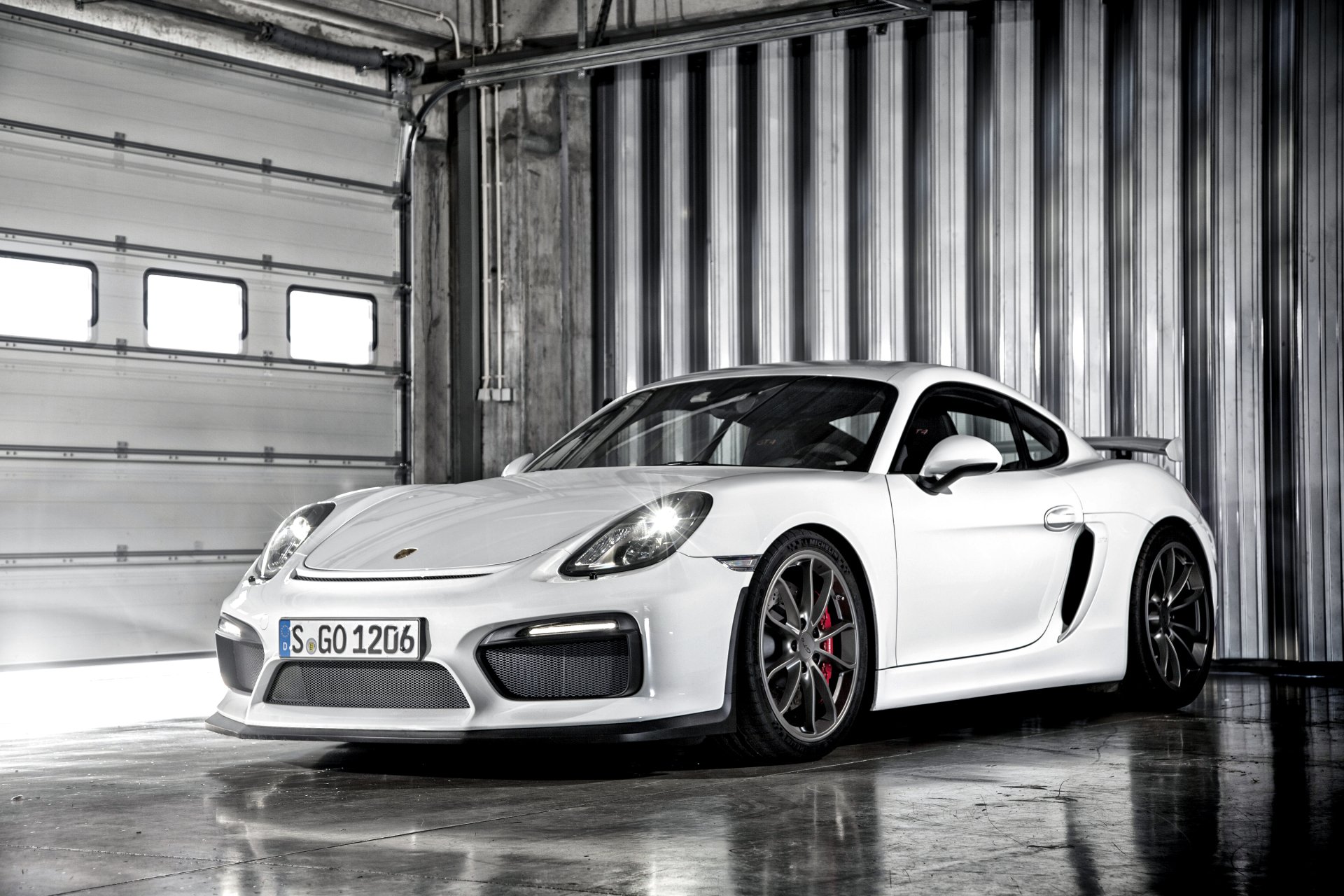 White Porsche Cayman GT4 sports car in an industrial garage — 2K Quad HD PC desktop wallpaper featuring the Porsche vehicle.