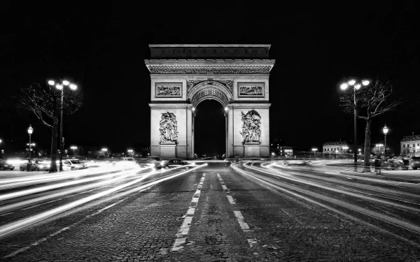 Black and white 4K Ultra HD night time-lapse of the Arc de Triomphe in Paris, France, capturing light trails on the monument's surrounding road.