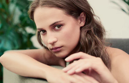 A close-up of Alicia Vikander, a Swedish actress with brown eyes and brunette hair, set against a bokeh background, creating an elegant HD desktop wallpaper.