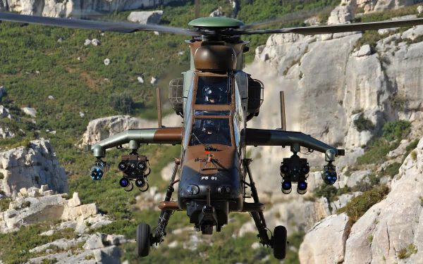 Front view of a Eurocopter Tiger attack helicopter in military camouflage, armed and hovering over rocky terrain — 2K Quad HD PC desktop wallpaper background.