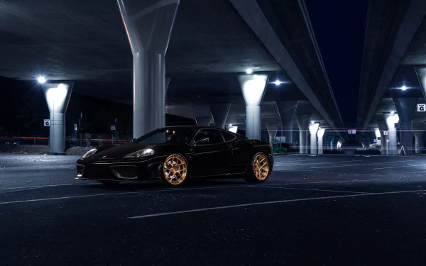 Black Ferrari 360 Modena supercar with gold rims parked under an urban bridge at night, showcased as an HD PC desktop wallpaper and background.