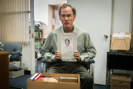 2K Quad HD PC desktop wallpaper: scene from the movie Spotlight (2015) — a man in an office holds a portrait amid boxes and files.