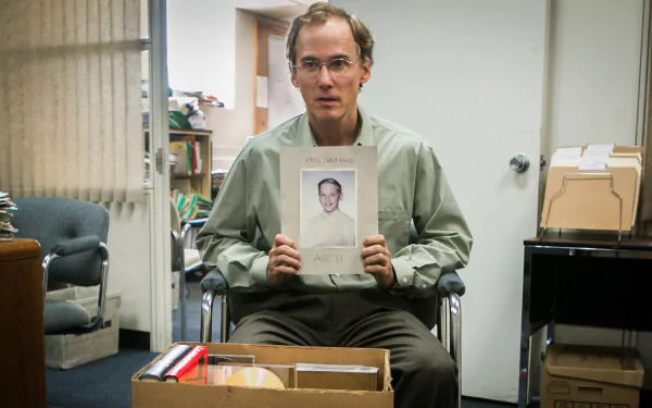 2K Quad HD PC desktop wallpaper: scene from the movie Spotlight (2015) — a man in an office holds a portrait amid boxes and files.