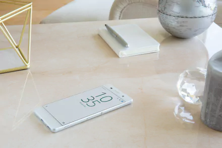 A Sony Xperia phone displaying the time on a light-colored desk, featured as an HD PC desktop wallpaper showcasing sleek technology.