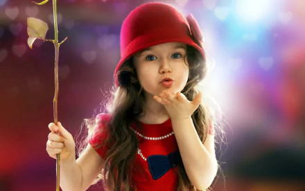 HD wallpaper featuring a cute little girl in a red hat, blowing a kiss while holding a stick. The colorful, dreamy background enhances the photography's charm.