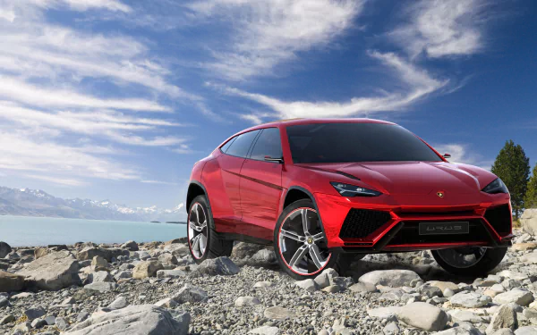 A striking red Lamborghini Urus SUV stands boldly on rocky terrain, set against a dramatic sky, showcased as a stunning 4K Ultra HD PC desktop wallpaper.