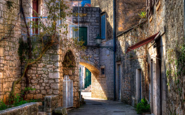 A serene street scene in Croatia featuring charming stone buildings and a curved archway, captured in stunning 4K Ultra HD, perfect as a desktop wallpaper.