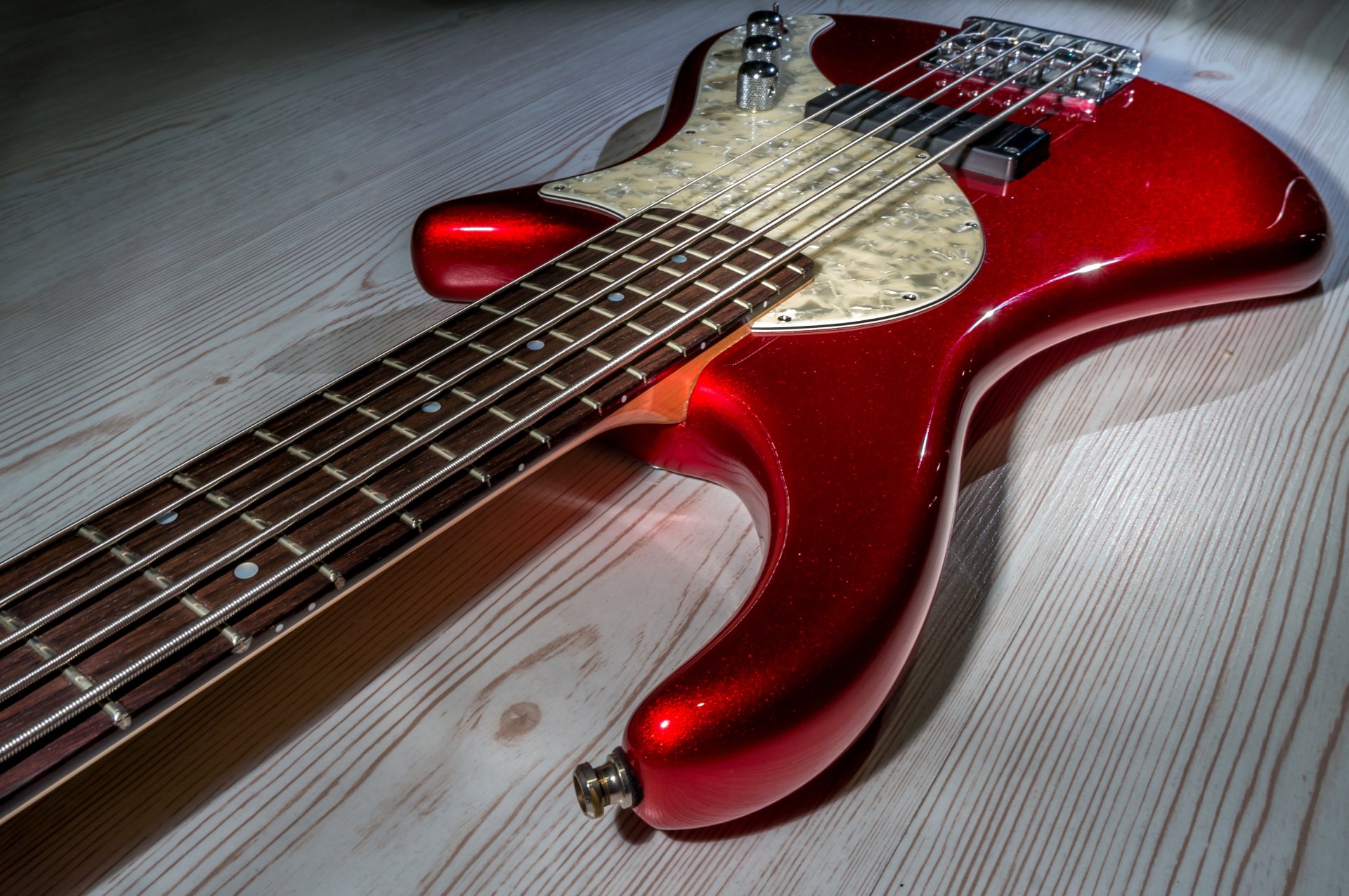 Close-up of glossy red electric guitar resting on a light wood floor, showcasing neck, frets and pickups — instrument, music; 4K Ultra HD PC desktop wallpaper/background.