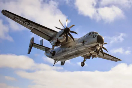 HD PC desktop wallpaper: low-angle airplane/aircraft shot of a Northrop Grumman C-2 Greyhound Navy military transport in flight against a blue sky.