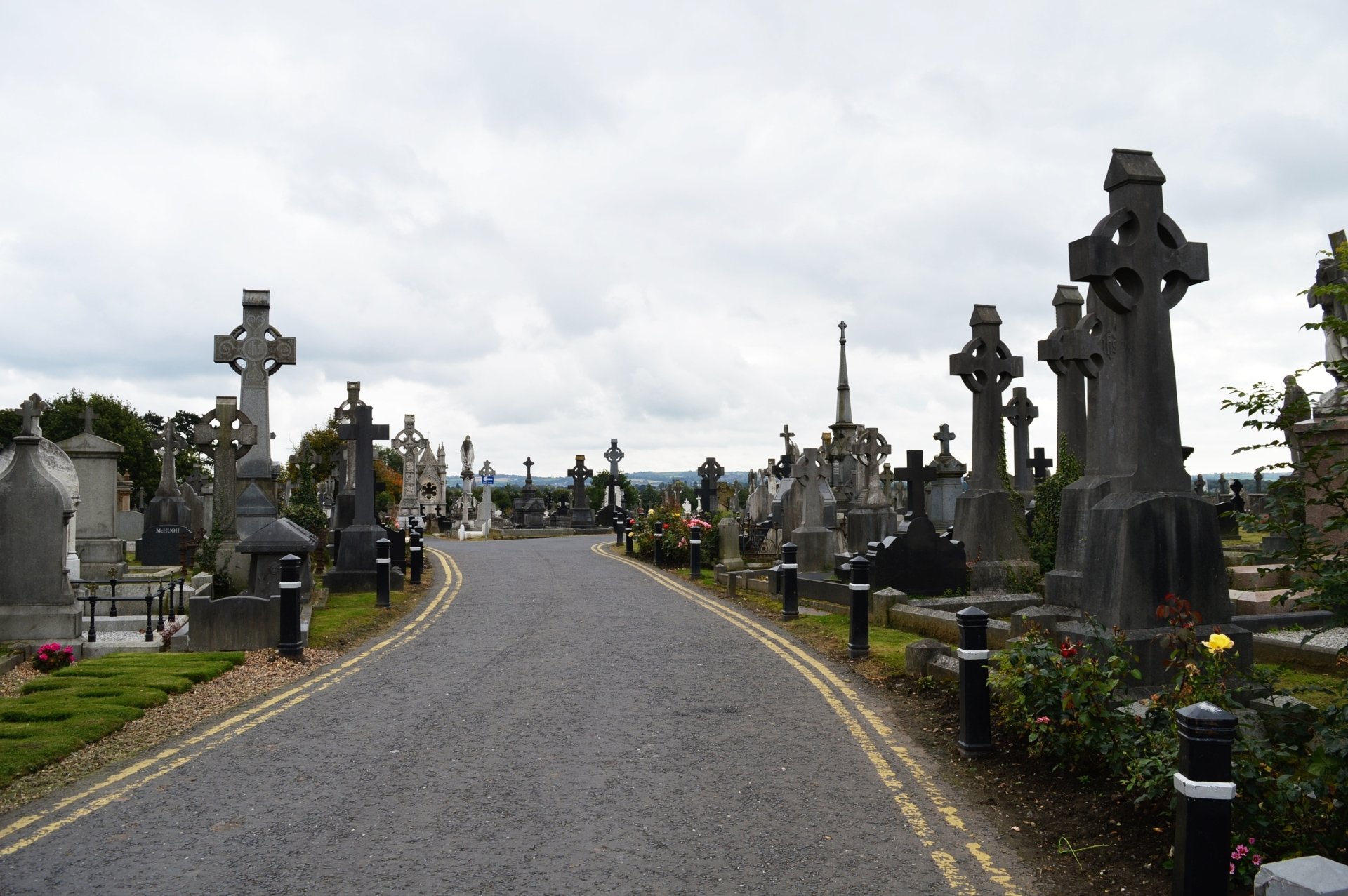 HD desktop wallpaper featuring a cemetery road lined with religious headstones and crosses under a cloudy sky.