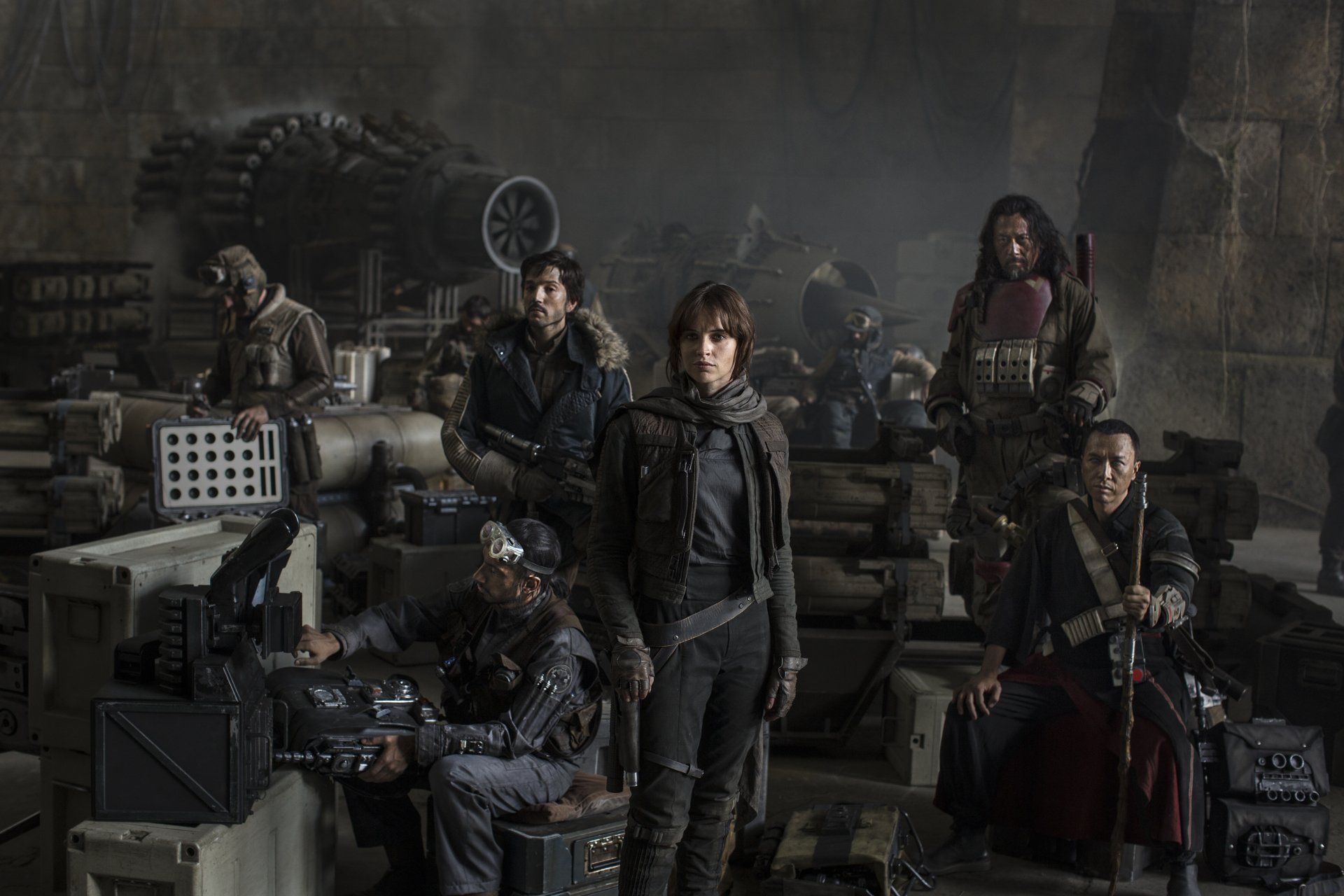 Group of characters from *Rogue One: A Star Wars Story*, featuring Jyn Erso (Felicity Jones), Chirrut Îmwe (Donnie Yen), and others, set in a dramatic, shadowy background. HD wallpaper.