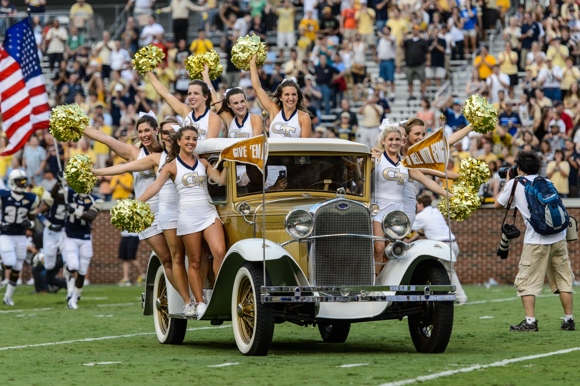 Ford vintage car carrying Georgia Tech cheerleaders with pom-poms on a football field, captured in vibrant 4K Ultra HD for a dynamic sports desktop wallpaper.