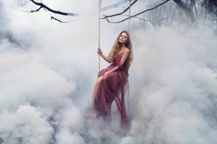 A blonde woman wearing a crown sits gracefully on a swing surrounded by thick fog and clouds in a fantasy-themed, artistic HD desktop wallpaper.