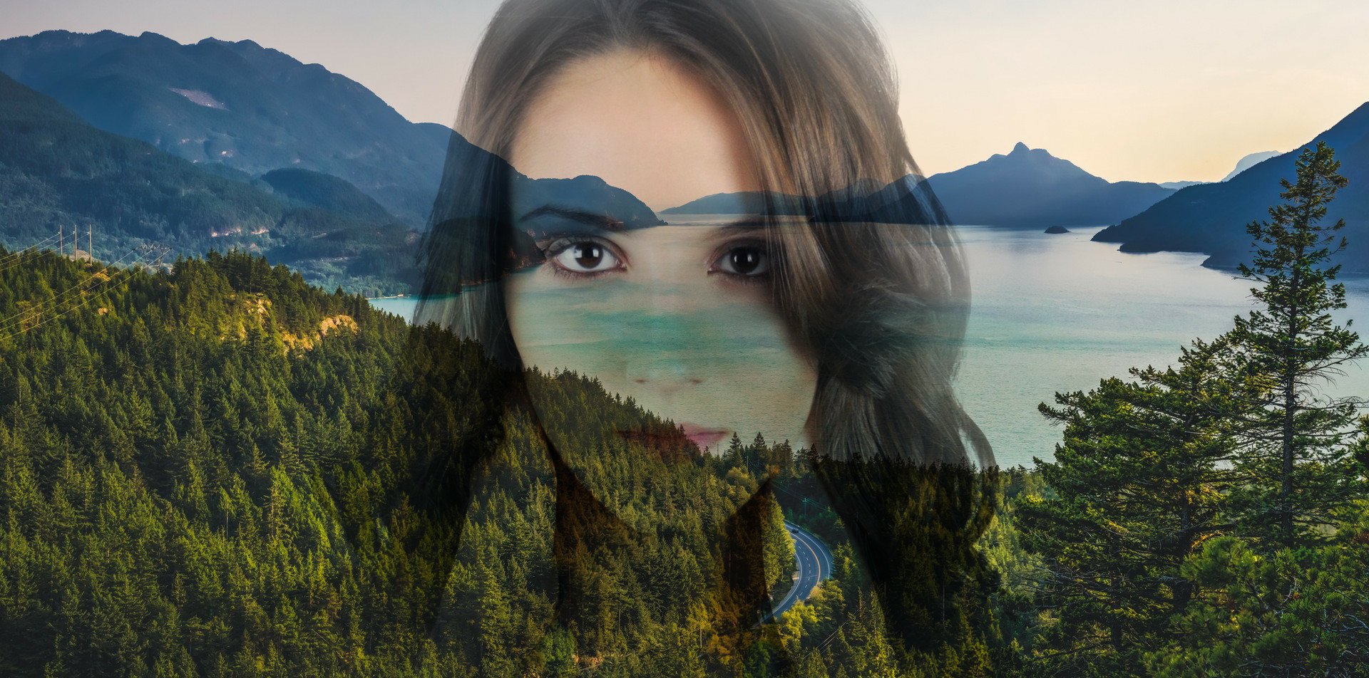 HD PC desktop wallpaper: double-exposure forest photography manipulation blending a mountain lake, evergreen road and a translucent woman's face centered over the landscape.