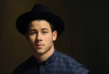 HD desktop wallpaper featuring a portrait of a man in a black hat and blue shirt with subtle lighting, providing a moody background ambiance.