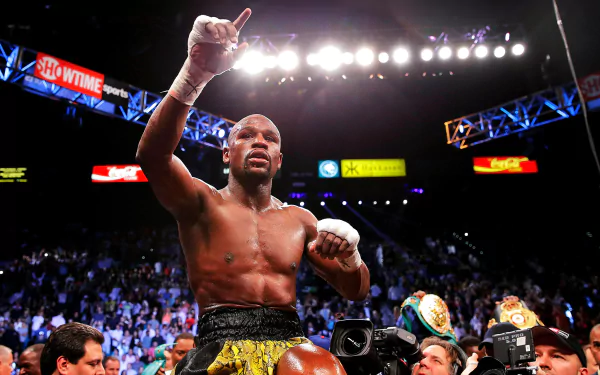 HD desktop wallpaper of a victorious boxer in the ring, pointing up, amid a cheering audience backdrop.