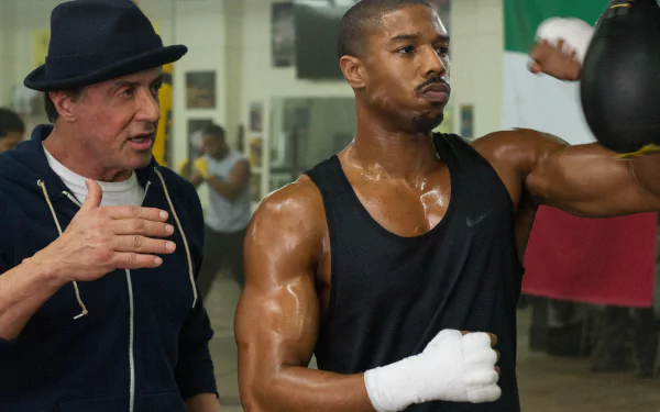Creed movie gym scene: Rocky Balboa coaching Adonis Creed as the young boxer trains, intense 2K Quad HD desktop wallpaper.