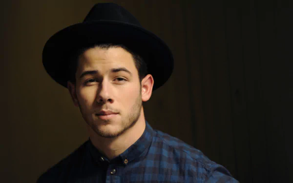 HD desktop wallpaper featuring a portrait of a man in a black hat and blue shirt with subtle lighting, providing a moody background ambiance.