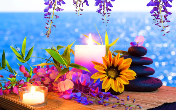 A serene still life featuring a vibrant yellow flower, smooth stones, and candles, set against a tranquil ocean backdrop. A captivating HD wallpaper for a calming atmosphere.