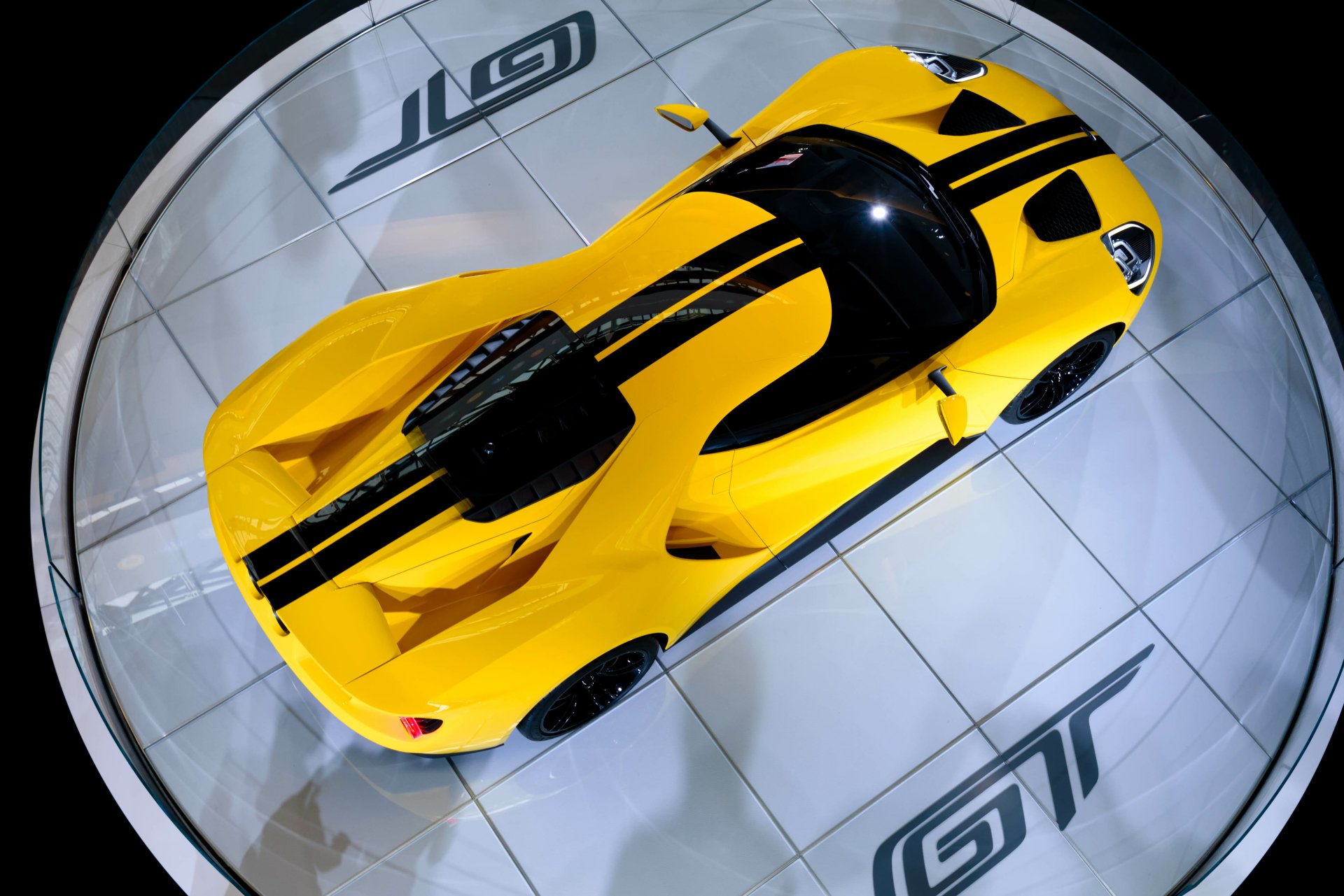 Top-down view of a yellow Ford GT supercar with black racing stripes, showcased as a sleek 4K Ultra HD PC desktop wallpaper and background.