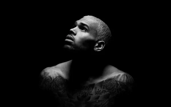 A striking HD wallpaper featuring Chris Brown, showcasing his impressive tattoos against a dark background, capturing an intense and contemplative expression.
